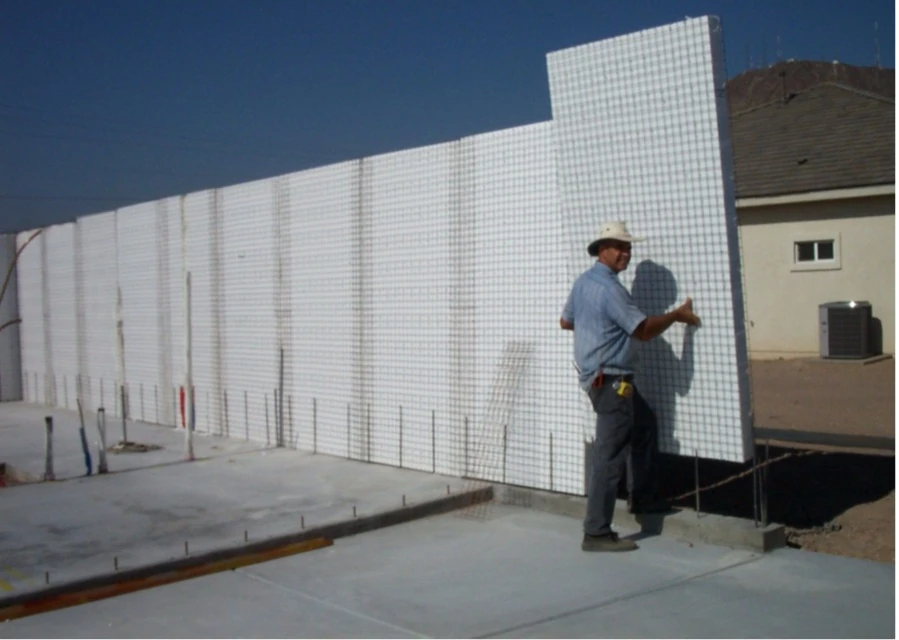 Installer positioning a structural concrete insulated panel on a building foundation